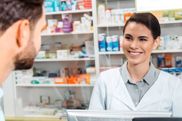 药剂师在药房柜台对顾客微笑的选择性焦点 — 图库照片