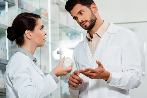 Farmacêutico Mostrando Colega Frasco Pílulas Por Vitrine Farmácia — Fotografia de Stock