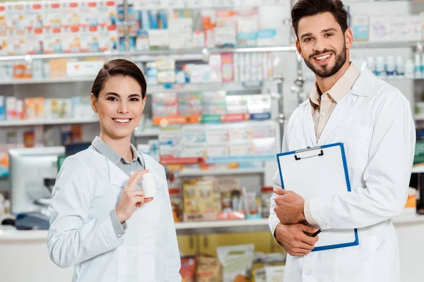 Farmacêuticos Sorridentes Com Prancheta Pílulas Olhando Para Câmera Farmácia — Fotografia de Stock