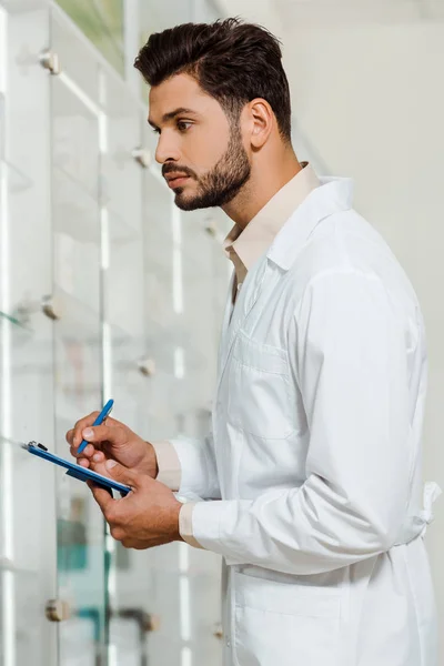 Vista Laterale Del Bel Farmacista Con Appunti Guardando Vetrina Farmacia — Foto Stock