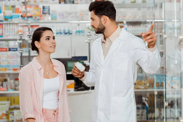 Druggist Holding Jar Pills Pointing Showcase Customer — Stock Photo, Image