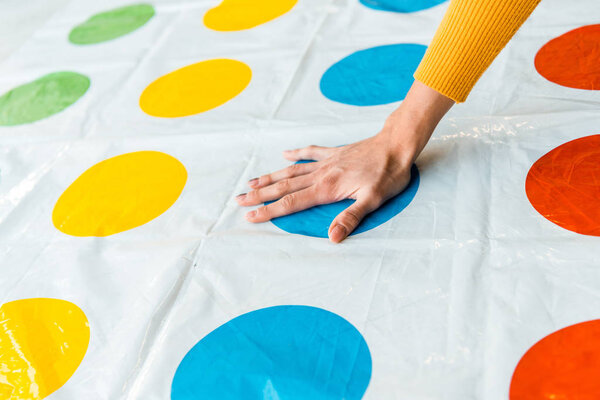 KYIV, UKRAINE - NOVEMBER 22, 2019: cropped view of woman putting hand on blue circle while playing twister game 