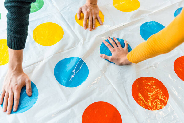 KYIV, UKRAINE - NOVEMBER 22, 2019: cropped view of man and woman putting hands on circles while playing twister game 