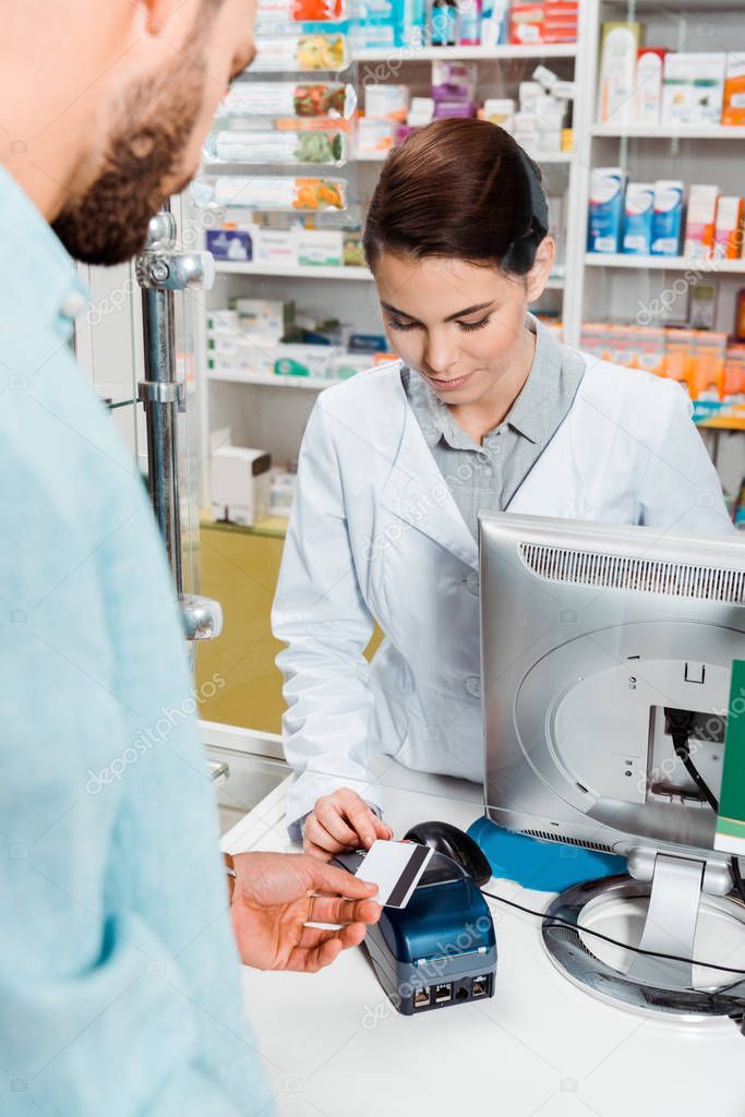 Selective focus of customer with credit card using paypass in pharmacy