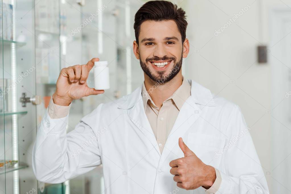 Pharmacist with jar of pills smiling at camera and showing thumb up 
