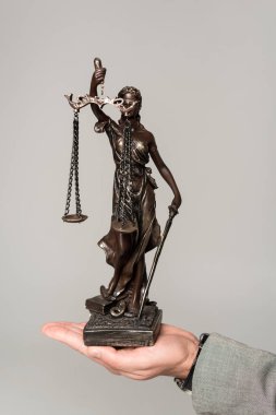 cropped view of lawyer holding themis statue isolated on grey clipart