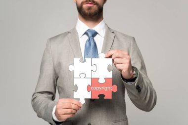 Telif hakkı harfleri gri renkli yapboz tutan işadamının kısmi görüntüsü