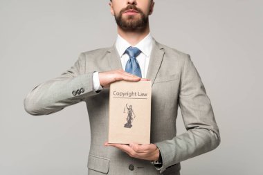 partial view of lawyer holding book with copyright law title isolated on grey clipart