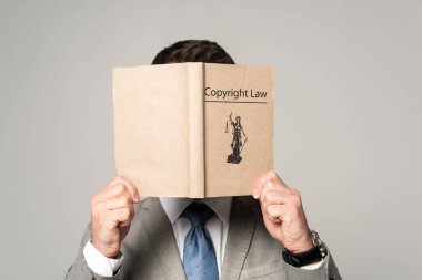 Gri renkte izole edilmiş telif hakkı kitabıyla yüzünü gizleyen avukat