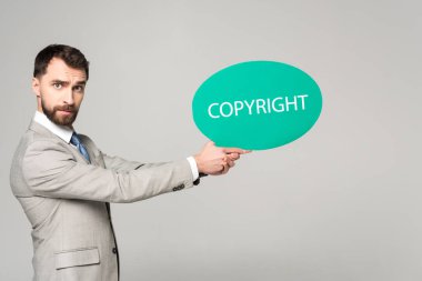 serious businessman holding thought bubble with copyright inscription isolated on grey clipart