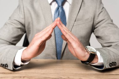 cropped view of businessman showing protection gesture isolated on grey clipart