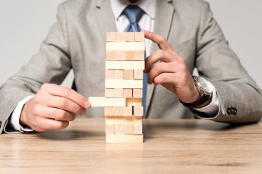 Gri üzerine izole edilmiş tahta kule oyunu oynayan işadamının kırpılmış görüntüsü