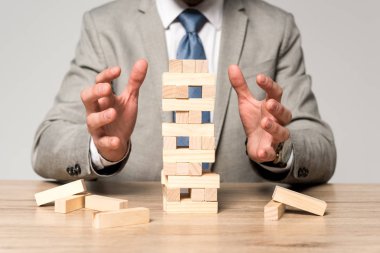 Gri üzerine izole edilmiş odun kulesi yakınlarında oturan işadamının kısmi görüntüsü