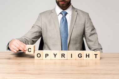 Gri üzerinde telif hakkı saklı tahta küplerin yanında oturan işadamının kırpılmış görüntüsü