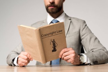 partial view of lawyer reading book with copyright law title isolated on grey clipart
