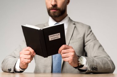 Gri üzerine izole edilmiş fikri mülkiyet unvanına sahip hukuki kitap okuyan işadamı görüşü