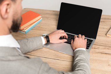Gri ekranda boş ekranlı dizüstü bilgisayar kullanan işadamının kırpılmış görüntüsü