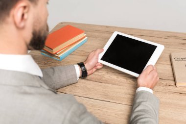 Gri ekranda boş ekranlı dijital tablet tutan işadamının kırpılmış görüntüsü