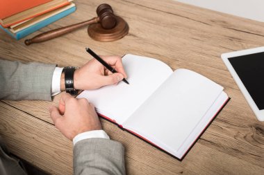 Avukatın ahşap masaya defter yazması.