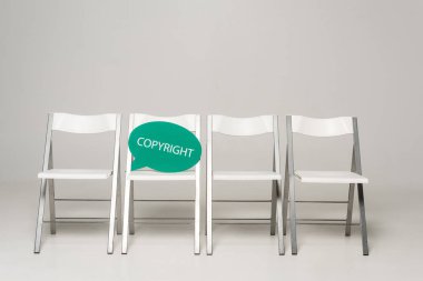 Gri arkaplanda telif hakkı yazılı sıra sandalye ve düşünce balonu