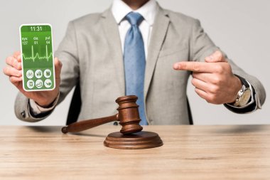Kalp atışı uygulaması olan akıllı telefonu işaret eden avukat görüşü ve masa başında tokmak.