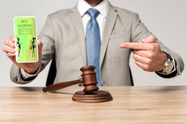 En iyi alışveriş uygulaması olan akıllı telefonu işaret eden avukat görüşü ve masa başındaki yargıç Gavin.