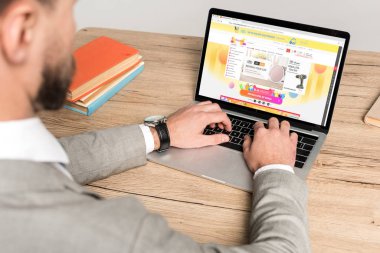 Kyiv, Ukrayna - 25 Kasım 2019: Gri ekranda Aliexpress web sitesi olan dizüstü bilgisayar kullanan işadamının kırpılmış görüntüsü