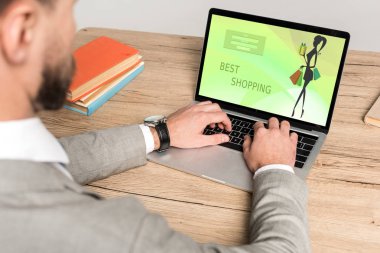 Gri ekranda en iyi alışveriş sitesine sahip dizüstü bilgisayar kullanan işadamının kırpılmış görüntüsü