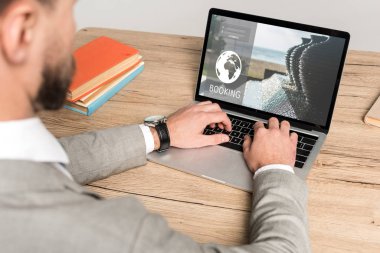 Gri ekranda rezervasyon web sitesi kullanan işadamının kırpılmış görüntüsü