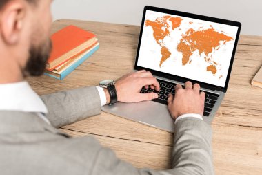 Ekranda dünya haritası olan bir dizüstü bilgisayar kullanan işadamı görüntüsü gride izole edildi