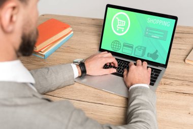 Gri ekranda alışveriş sitesi kullanan işadamının kırpılmış görüntüsü