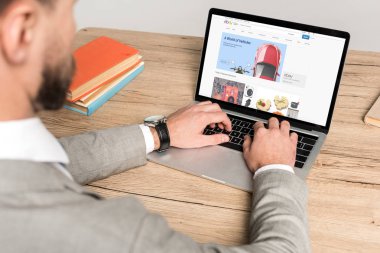 Kyiv, Ukrayna - 25 Kasım 2019: Gri ekranda Ebay web sitesi kullanan iş adamının kırpılmış görüntüsü