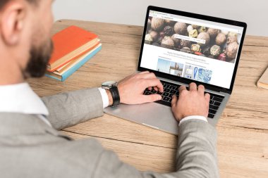 Kyiv, Ukrayna - 25 Kasım 2019: Gri ekranda depo fotoğrafları web sitesi kullanan iş adamının kırpılmış görüntüsü