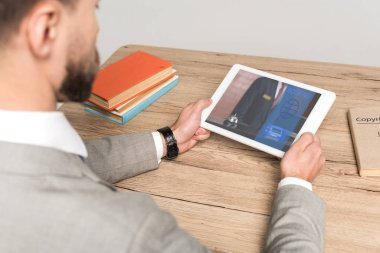 Gri ekranda izole edilmiş rezervasyon uygulaması ile dijital tablet kullanan işadamının kırpılmış görünümü
