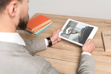 Gri ekranda izole edilmiş rezervasyon uygulaması ile dijital tablet kullanan işadamının kırpılmış görünümü