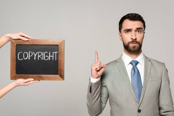 частичное представление женщины, держащей доску с авторской надписью рядом с бизнесменом, показывающей знак идеи, изолированный на сером
