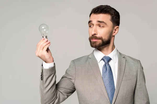 Skeptical Businessman Holding Light Bulb Isolated Grey — Stock Photo, Image