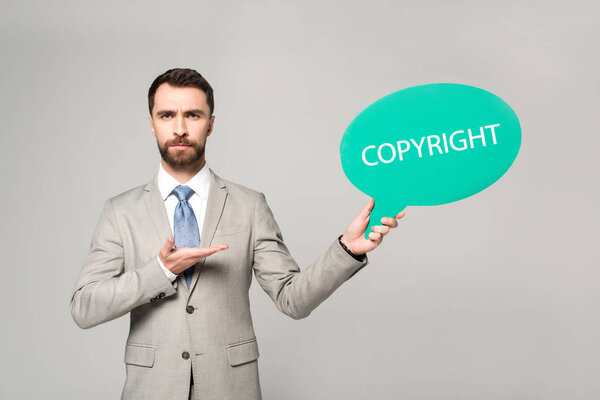 уверенный бизнесмен, указывая рукой на мыльный пузырь с авторской надписью, изолированной на сером
