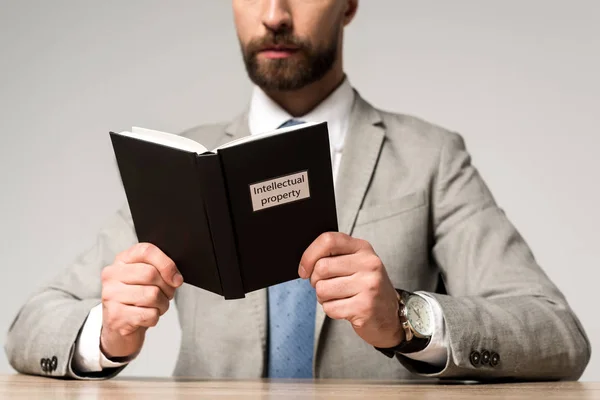 Pandangan sempit dari pengusaha membaca buku yuridis dengan judul kekayaan intelektual terisolasi di abu-abu — Stok Gambar Pandangan Sempit Dari Pengusaha Membaca Buku Yuridis Dengan Judul Kekayaan Stok Lukisan
