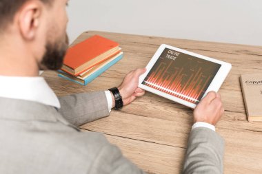 Gri ekranda çevrimiçi ticaret uygulaması olan dijital tablet kullanan işadamının kısmi görünümü
