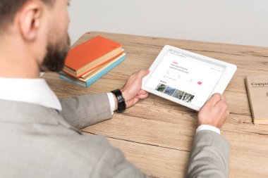 Kyiv, Ukrayna - 25 Kasım 2019: Gri ekranda Airbnb uygulaması ile dijital tablet kullanan işadamının kırpılmış görüntüsü