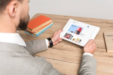 Kyiv, Ukrayna - 25 Kasım 2019: Gri ekranda Ebay uygulaması olan dijital tablet kullanan işadamının kırpılmış görüntüsü