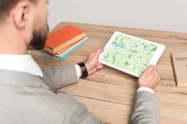 Gri ekranda haritalı dijital tablet kullanan işadamının kırpılmış görüntüsü