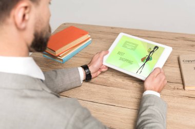 Gri ekranda çevrimiçi alışveriş uygulaması olan dijital tablet kullanan işadamının kısmi görünümü