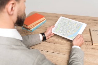 Gri ekranda haritalı dijital tablet kullanan işadamının kırpılmış görüntüsü