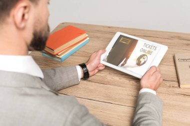 Gri ekranda izole edilmiş online uygulamalı dijital tablet kullanan işadamının kırpılmış görüntüsü