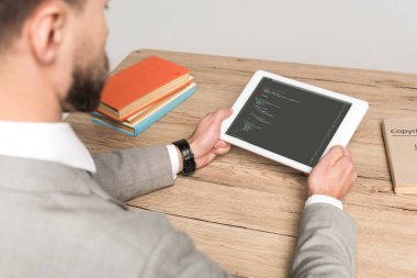 Kyiv, Ukrayna - 25 Kasım 2019: Gri ekranda Javascript ile dijital tablet kullanan programcının kırpılmış görüntüsü 