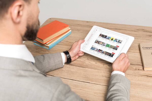 КИЕВ, Украина - 25 ноября 2019 года: обрезанный вид бизнесмена с помощью цифрового планшета с приложением Youtube на экране изолирован на сером
