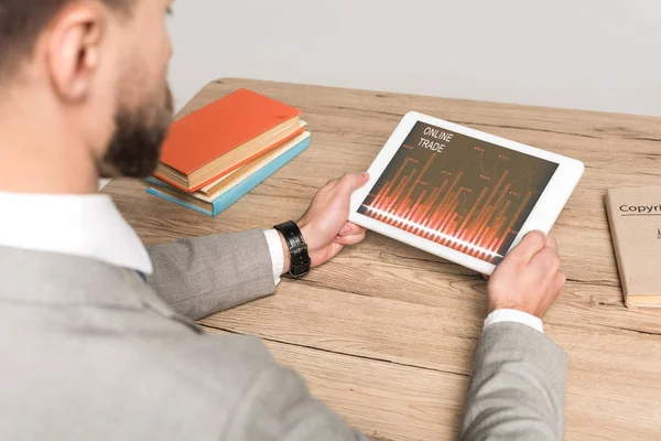 Gri ekranda çevrimiçi ticaret uygulaması olan dijital tablet kullanan işadamının kısmi görünümü