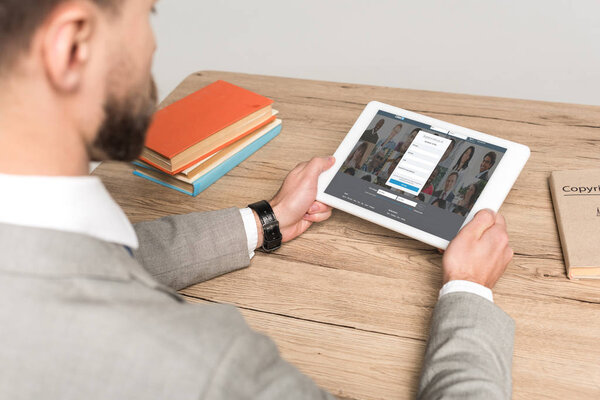 КИЕВ, Украина - 25 ноября 2019 года: обрезанный вид бизнесмена с помощью цифрового планшета с приложением Linkedin на экране изолирован на сером
